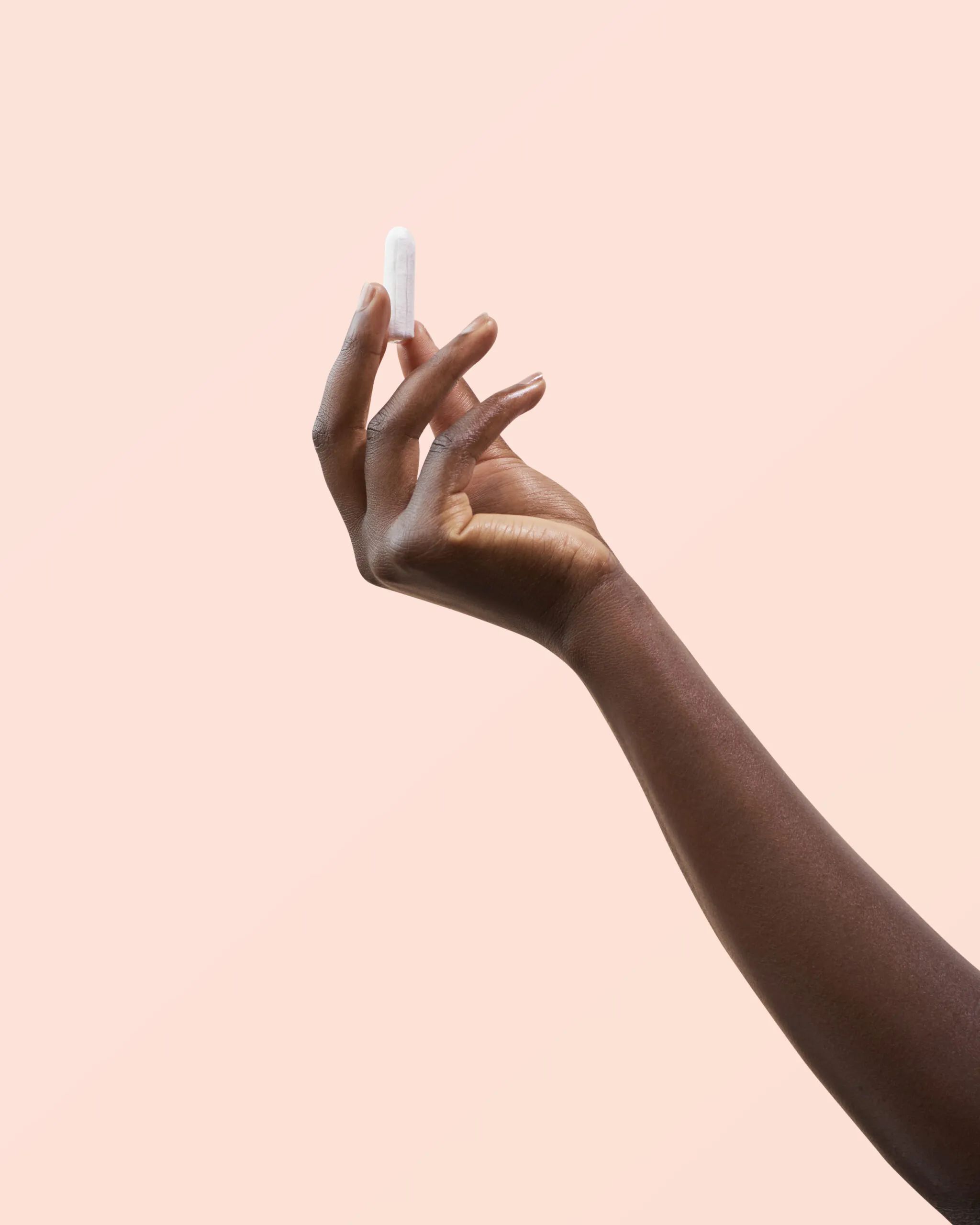 Une main tient un tampon blanc sur fond rose.