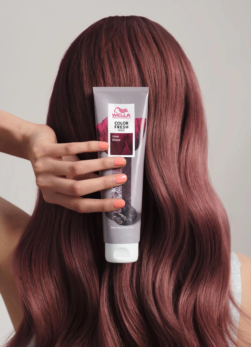Persoon houdt de Wella Color Fresh Mask Rose Blaze tube voor gekleurd haar. Lichte huid en gekleurde nagels.