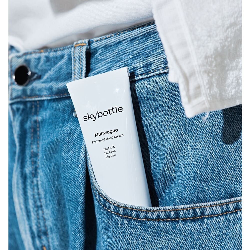 Tube blanc dans une poche de jean. Inscription: skybottle, Muhwagua Perfumed Hand Cream. Texte: Fig Fruit, Fig Leaf, Fig Tree.