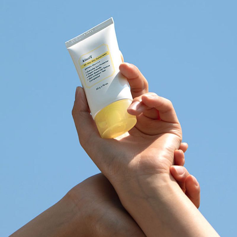 Handen houden een witte tube met gele dop vast. Opschrift: klairs All-day Airy Sunscreen SPF50+ PA++++. 50 g 1.76 oz.