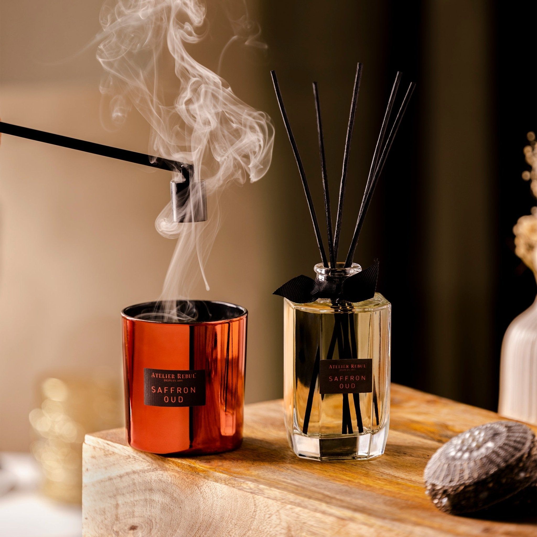 Une bougie et un diffuseur Atelier Rebul avec bâtonnets parfumés, tous deux au parfum Saffron Oud.