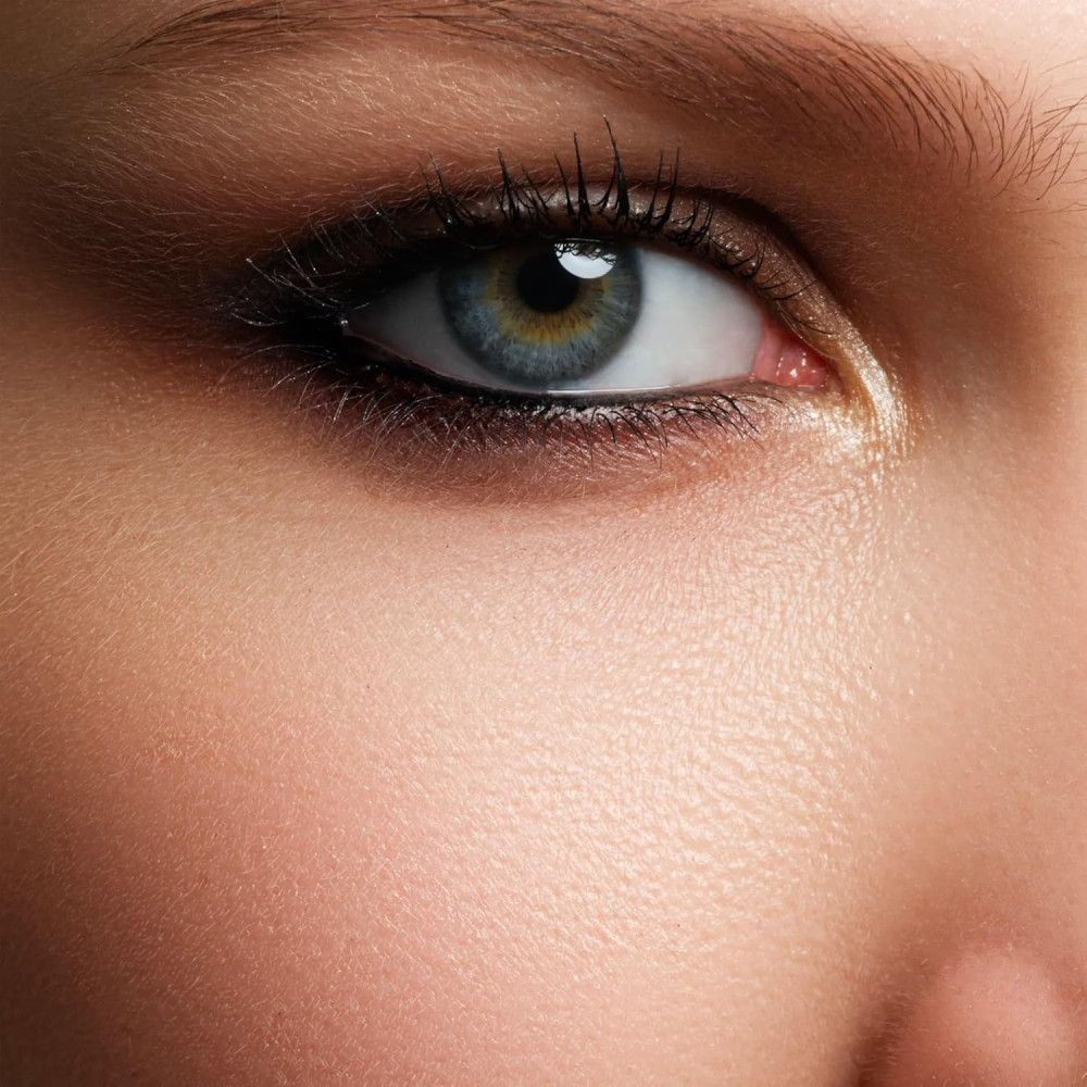 Gros plan d'un œil humain avec iris bleu-vert, mascara et eye-liner.