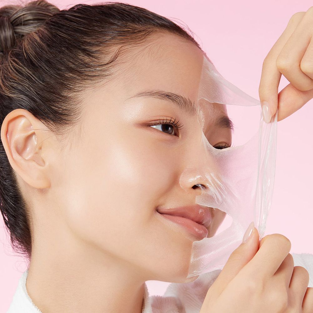 Vrouw die een transparant gezichtsmasker verwijdert. Huid is glanzend en gehydrateerd.