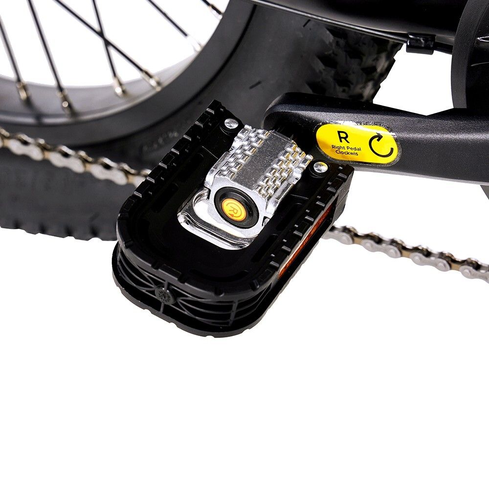 Close-up van een pedaal van een zwarte elektrische fiets. Zichtbaar: pedaal, reflector, gele sticker.