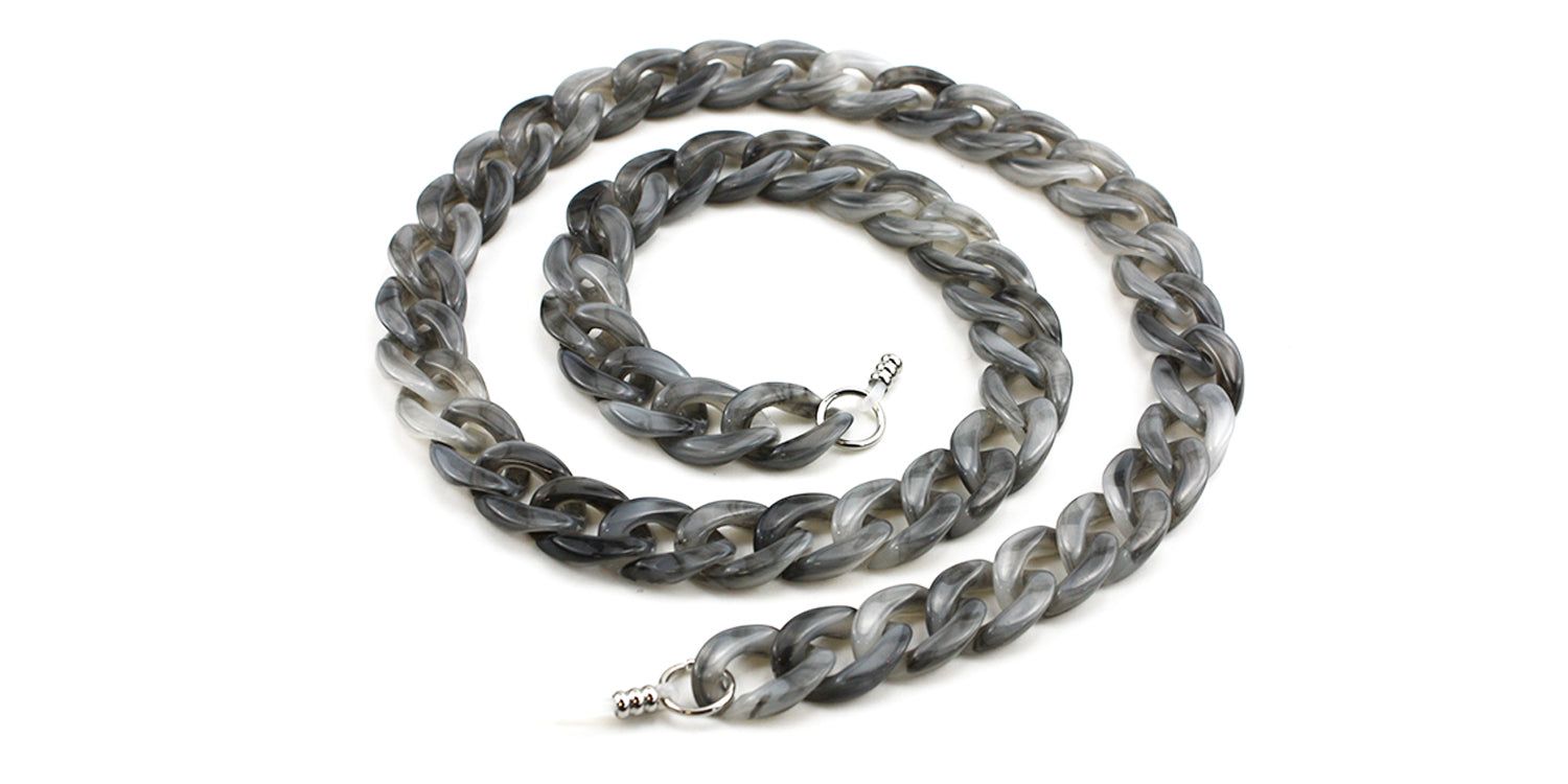 Chaîne de lunettes grise et chinée, composée de maillons. Fermoirs métalliques aux extrémités. Sur fond blanc.