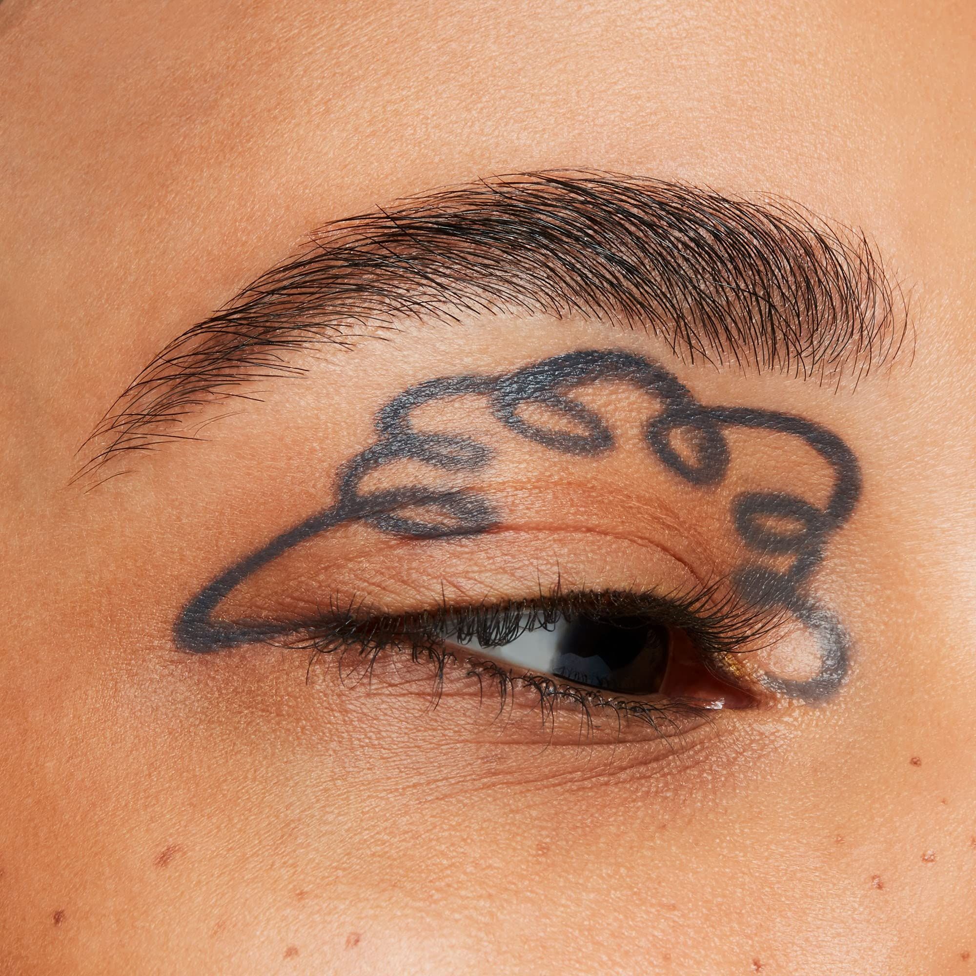 Œil avec un trait d'eye-liner gris. Le trait de liner forme une forme incurvée au-dessus de l'œil.