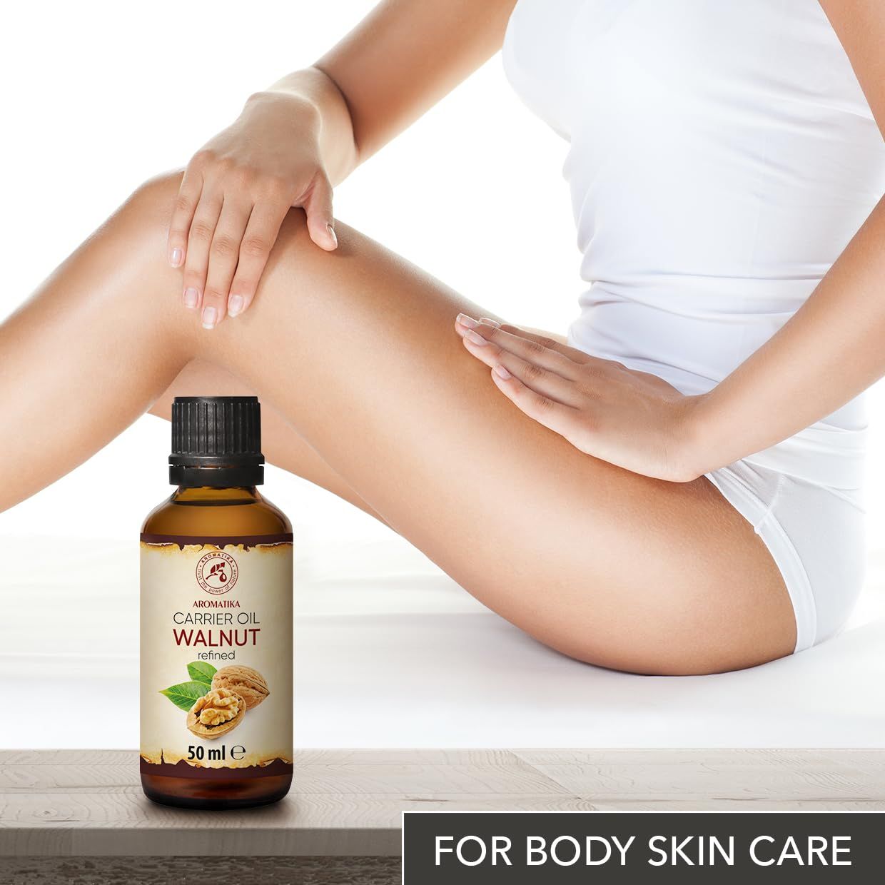 Flacon d'huile de noix AROMATIKA près de la jambe d'une femme, pour le soin du corps.