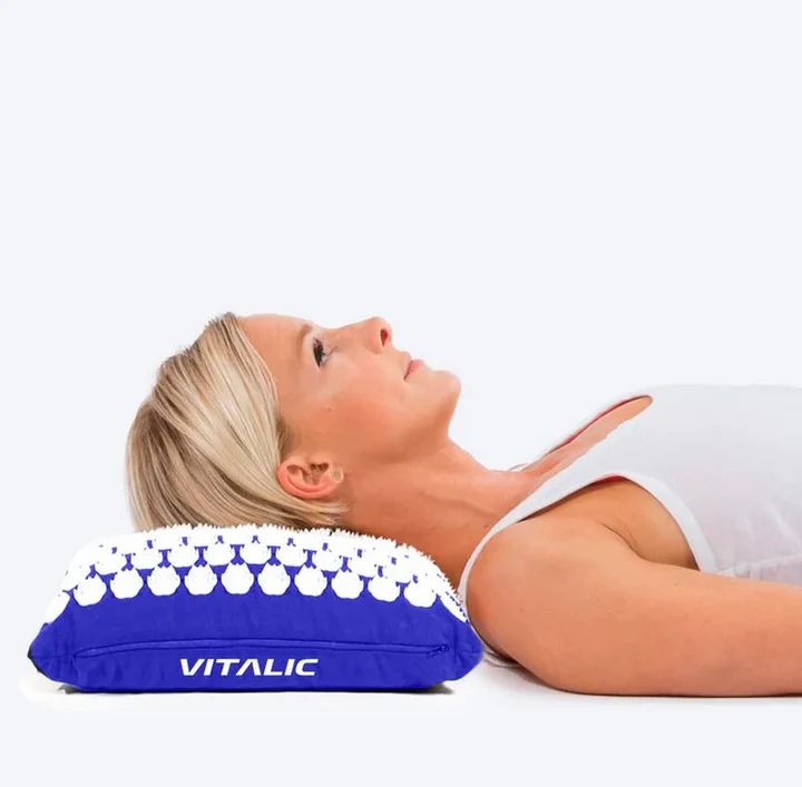 Vrouw ligt op blauw acupressuurkussen. Kussen met witte noppen. Opschrift: VITALIC.