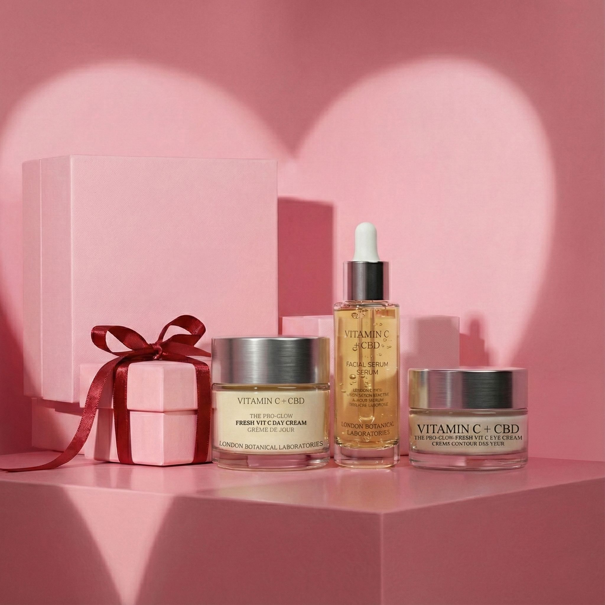 Cosmetische producten op roze sokkel. Dagcrème, oogcrème en serum. Cadeaudoos met strik. Achtergrond: hartvorm.