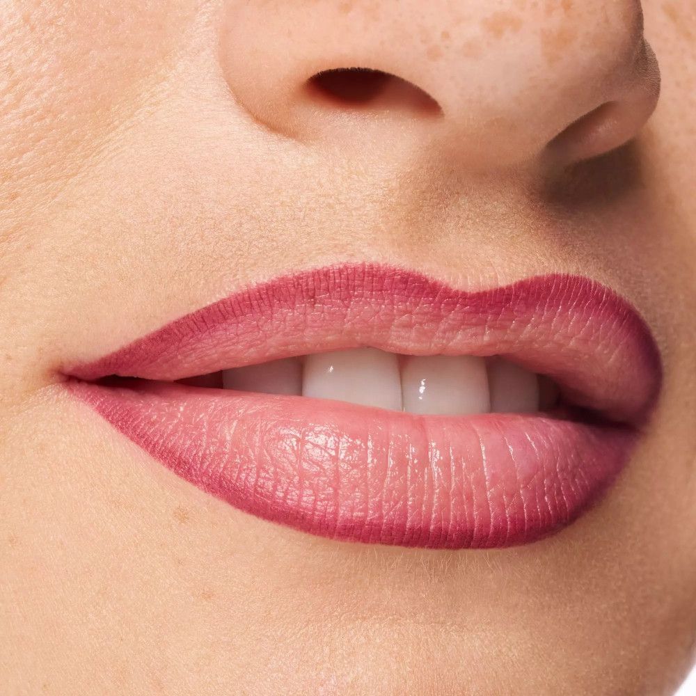 Close-up van lippen gecontourneerd met roze lippenstift. Witte tanden zichtbaar.