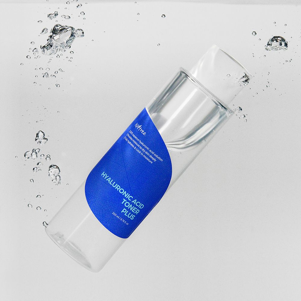 Flacon transparent avec étiquette bleue dans l'eau. Inscription: Hyaluronic Acid Toner Plus. Bulles.