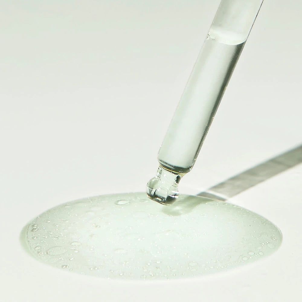 Pipet met serum op een oppervlak. Serum vormt een vlek. Geen fles zichtbaar.