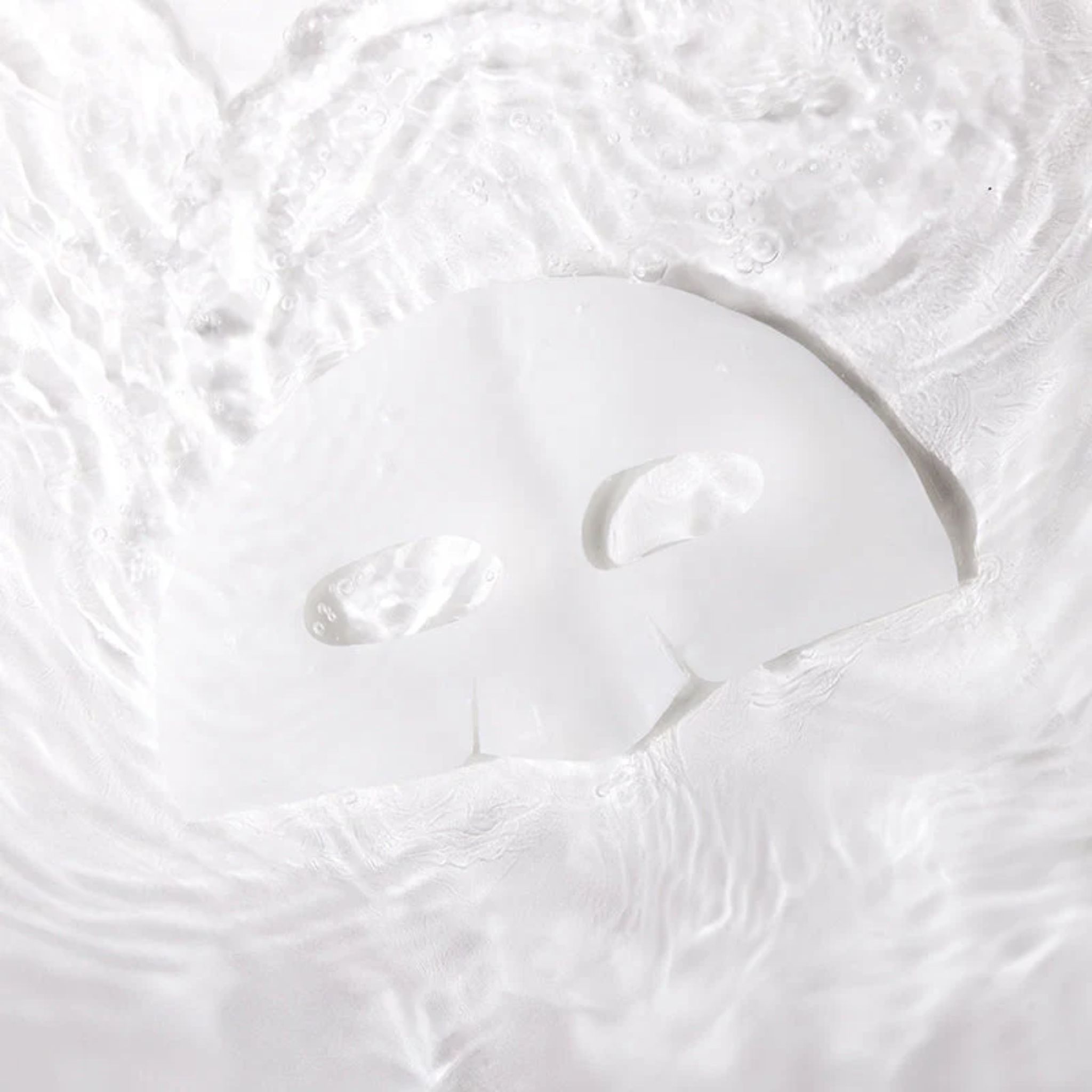 Un masque facial blanc flotte dans l'eau. Le masque a des ouvertures pour les yeux et la bouche. L'eau crée des vagues.