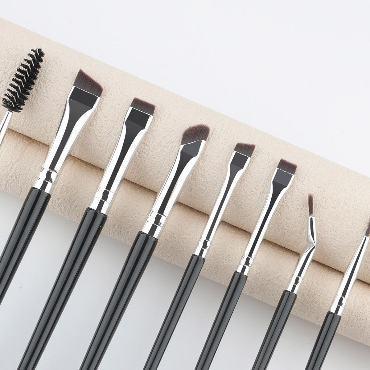 Ensemble de huit pinceaux de maquillage avec des manches noirs et des viroles argentées. Comprend une brosse et divers pinceaux biseautés et droits.