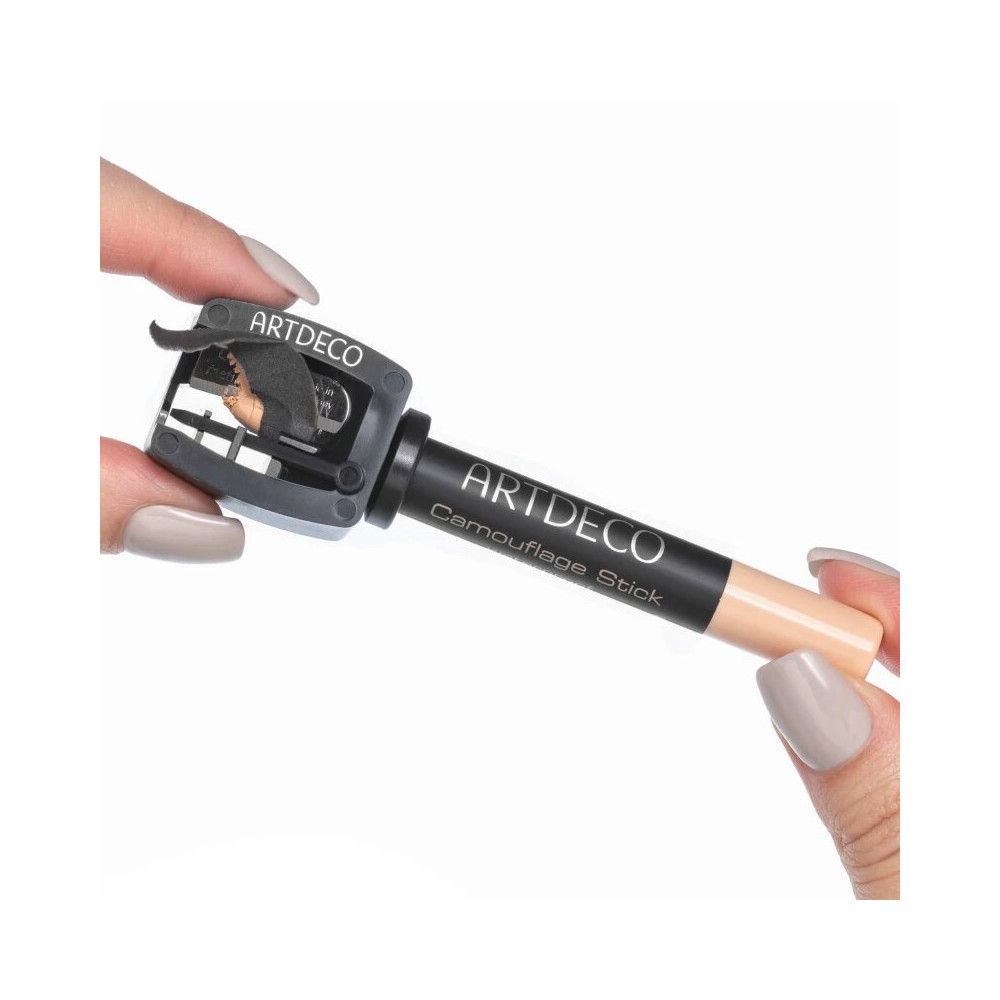 Mains tenant un crayon correcteur Artdeco et un taille-crayon. Taille-crayon avec logo Artdeco. Stick avec nom du produit.