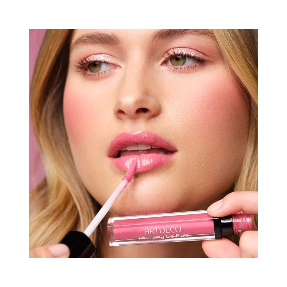 Femme appliquant le gloss Artdeco Plumping Lip Fluid 35 Juicy Berry. Lèvres roses, applicateur.
