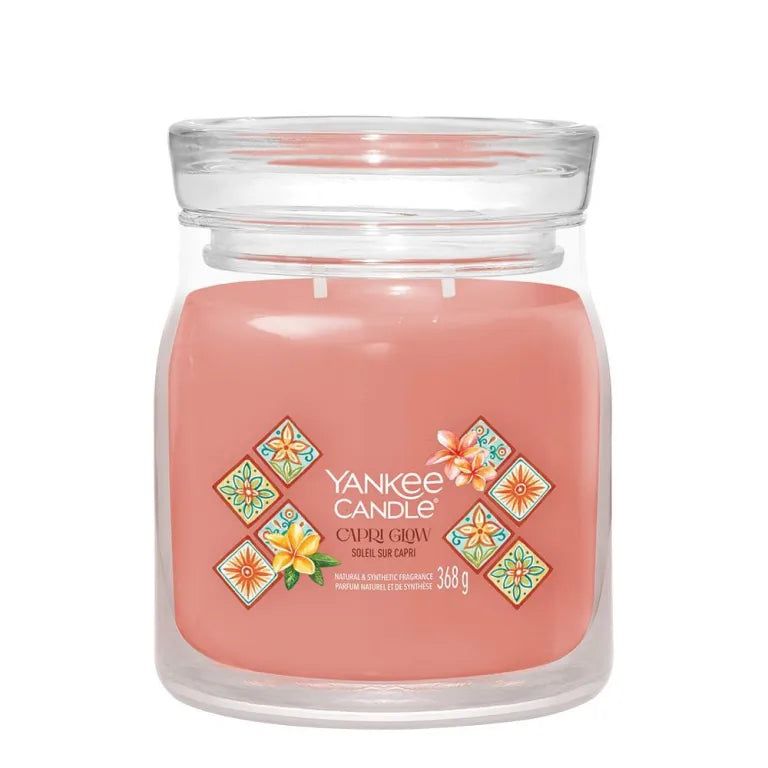 Yankee Candle Capri Glow. Bougie dans un verre. Hauteur : 11,5 cm. Montré devant une personne. Représentation grise.