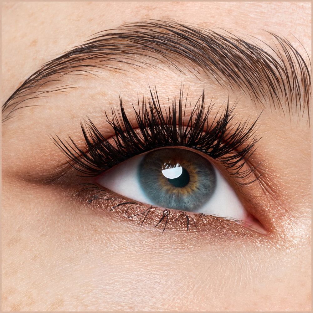Close-up van een oog met wimperextensions. Blauwe iris, donkere wimpers, zichtbare wenkbrauw.