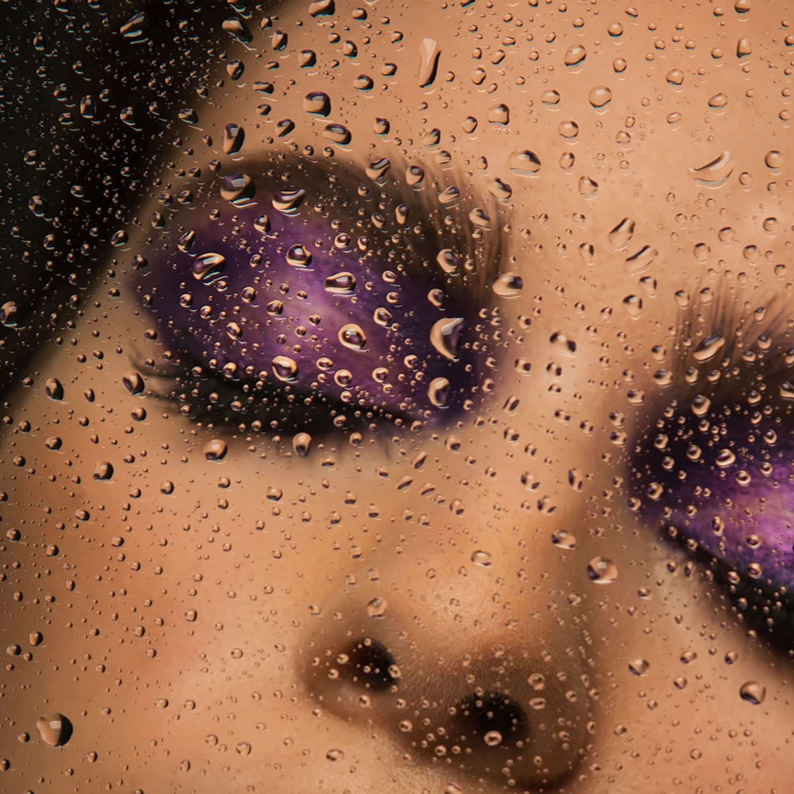 Ogen met paarse oogschaduw. Waterdruppels op een transparant oppervlak.