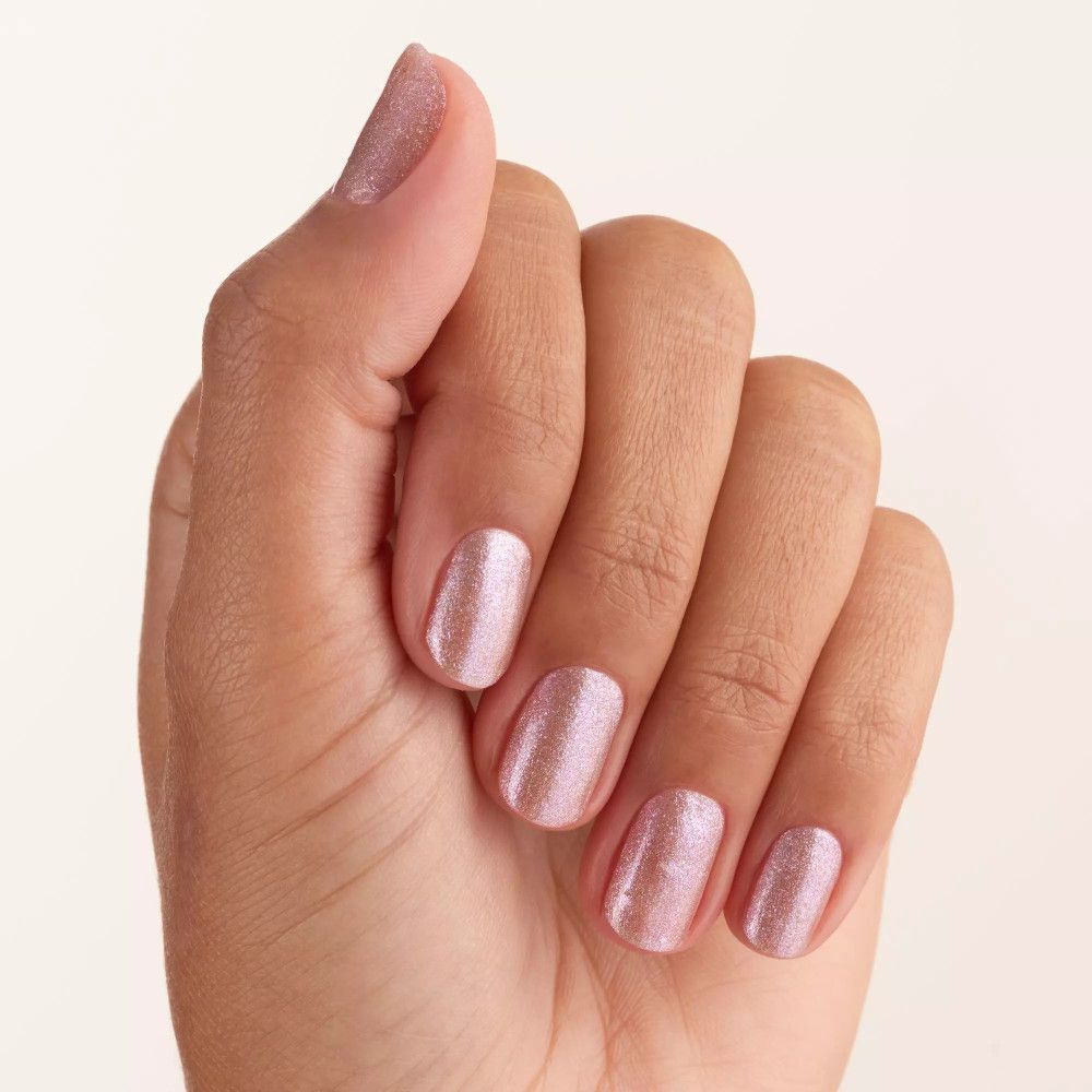Main avec ongles vernis. Vernis à ongles rose pailleté.
