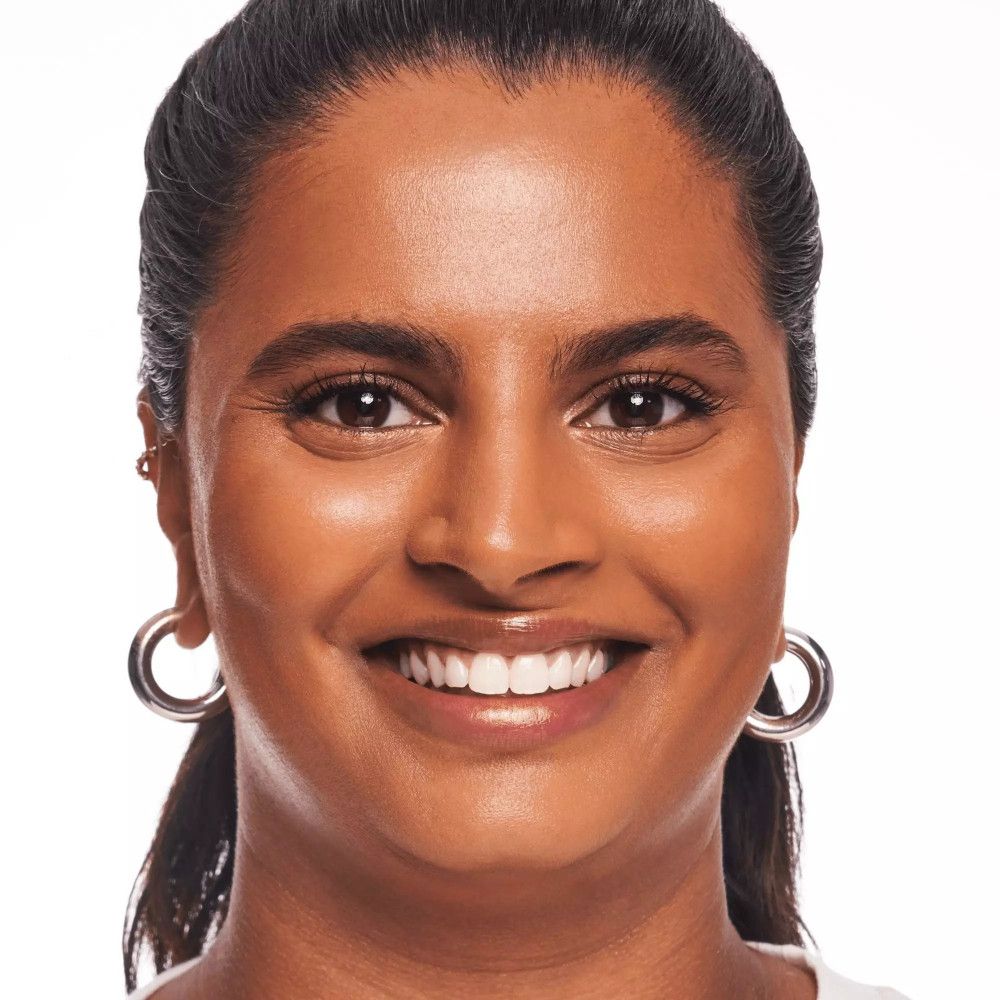 Portrait d'une femme avec fond de teint. Teint uniforme, peau brillante. Elle sourit.