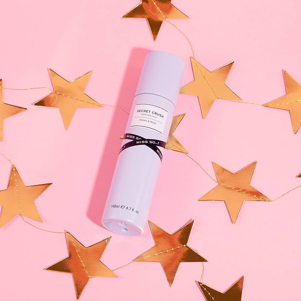 Lichtlila body mist met zwarte band. Opschrift: Secret Crush, Miss So. Omringd door gouden sterren op roze achtergrond.
