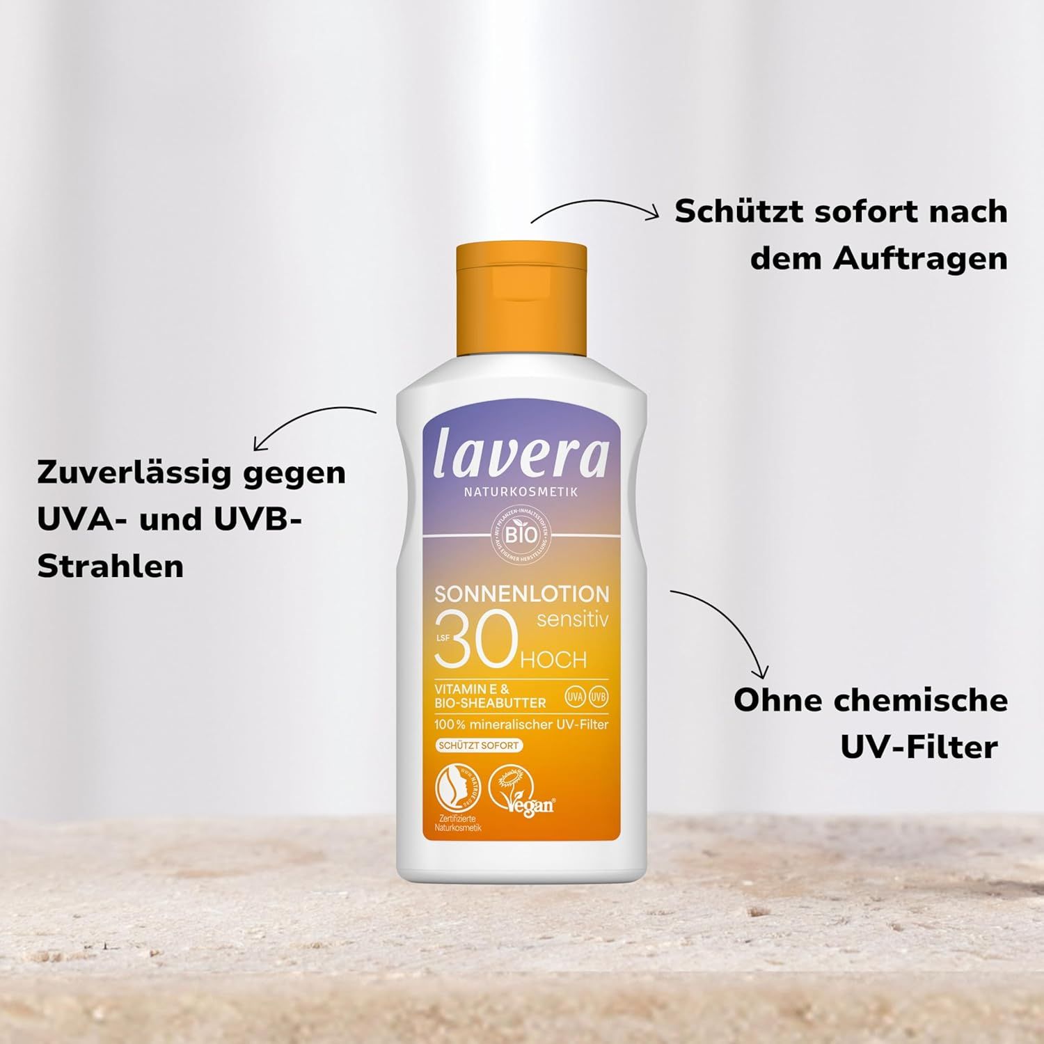 Lavera Sonnenlotion Sensitiv LSF 30 op zand. Tekst: UVA/UVB-bescherming, zonder chemische UV-filters.