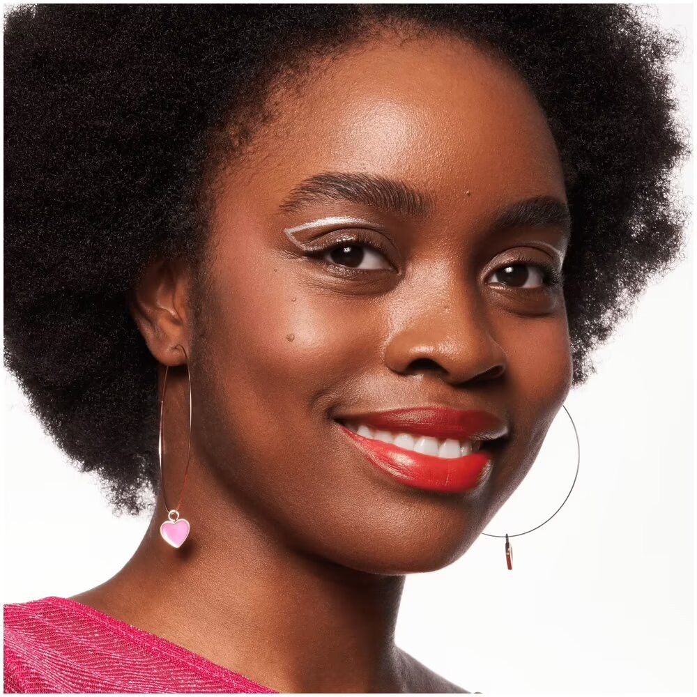 Portret van een vrouw met blush op wangen en lippen. Ze draagt opvallende eyeliner. Kijkt in de camera.