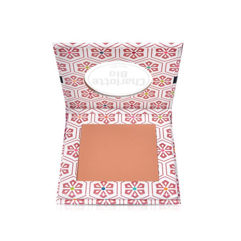Blush compact dans un emballage ouvert. Teinte rose pêche. Emballage à motifs floraux et texte de la marque.
