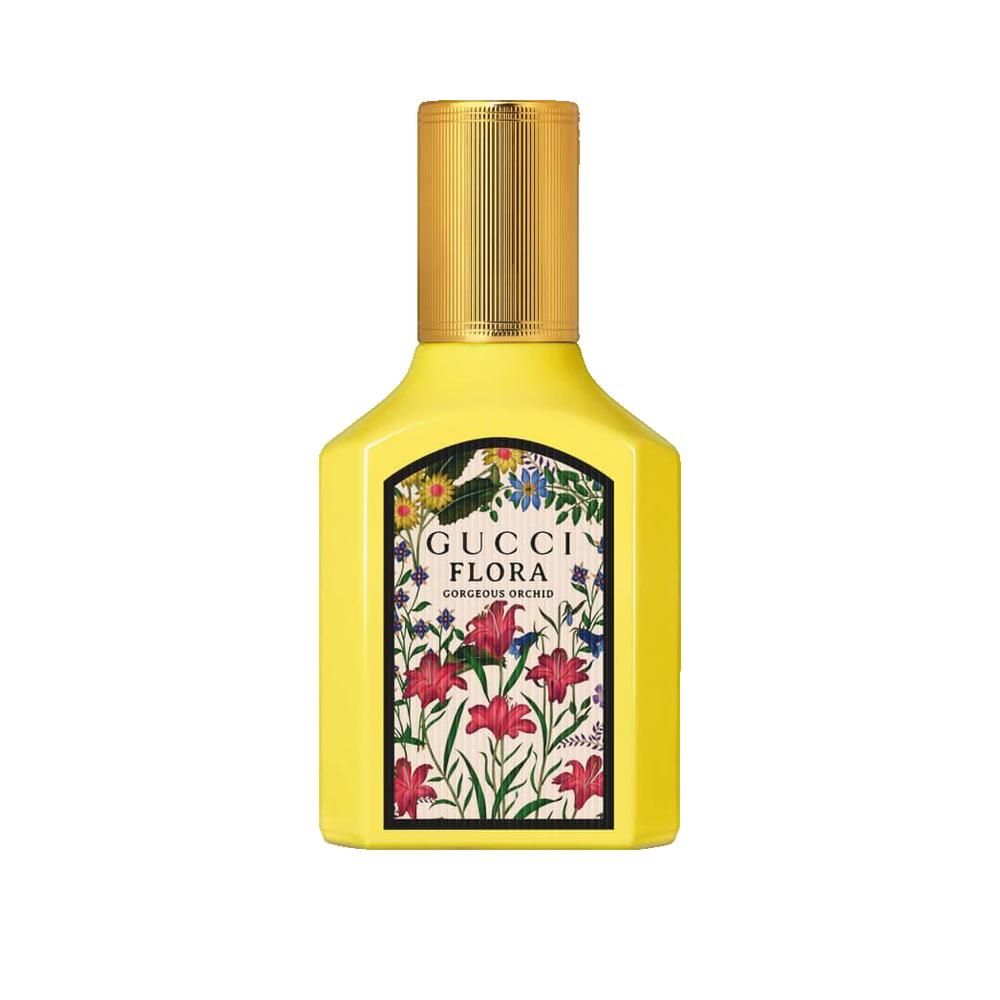 Flacon jaune avec bouchon doré. Étiquette avec motif floral et nom du produit. Forme carrée.