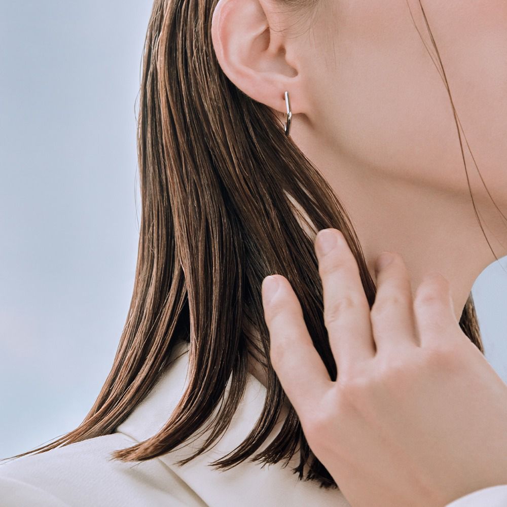 Close-up van een persoon die haar haar aanraakt. Het haar is nat en glanzend.