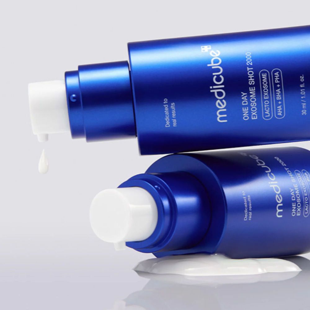 Twee blauwe flessen, productvloeistof druppelt. Productnaam en merk zichtbaar.