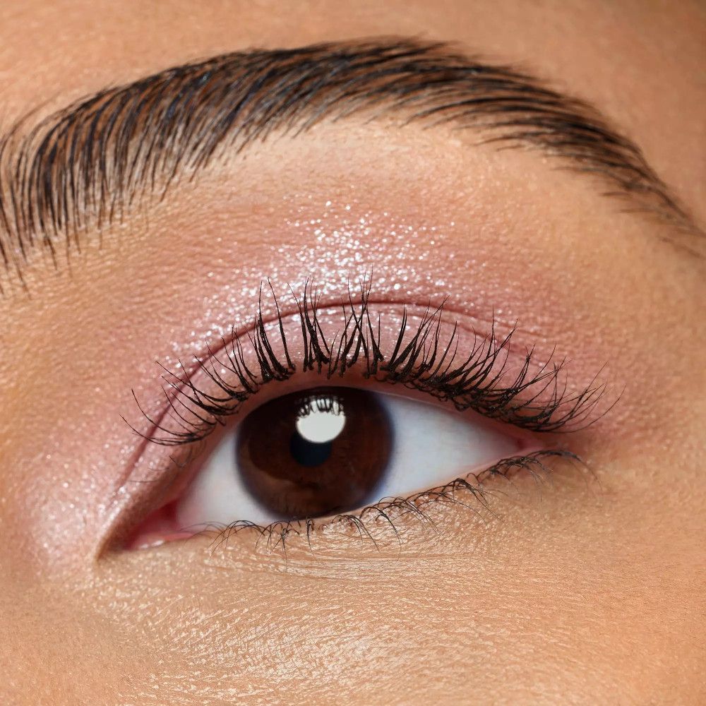 Gros plan d'un œil avec fard à paupières rose. Les cils sont maquillés. L'œil est marron.