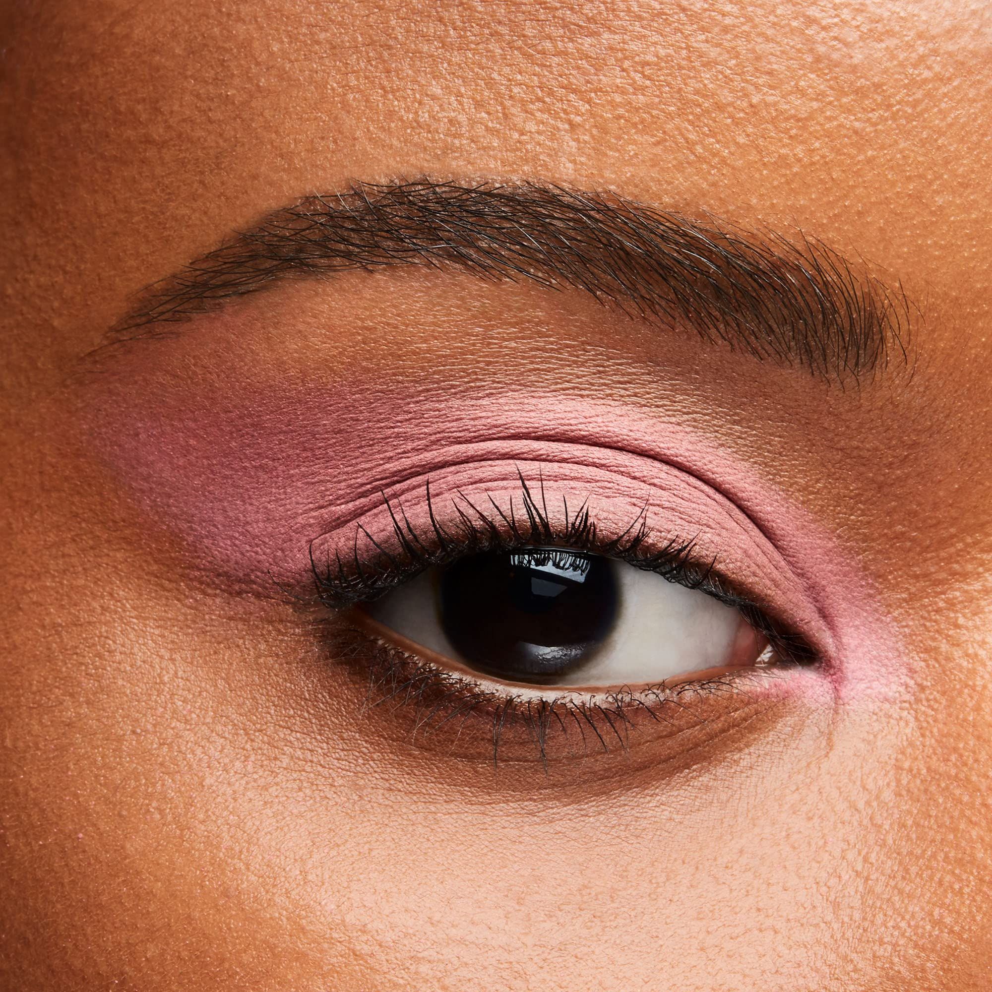 Œil avec fard à paupières rose. Sourcil brun, cils. Gros plan.