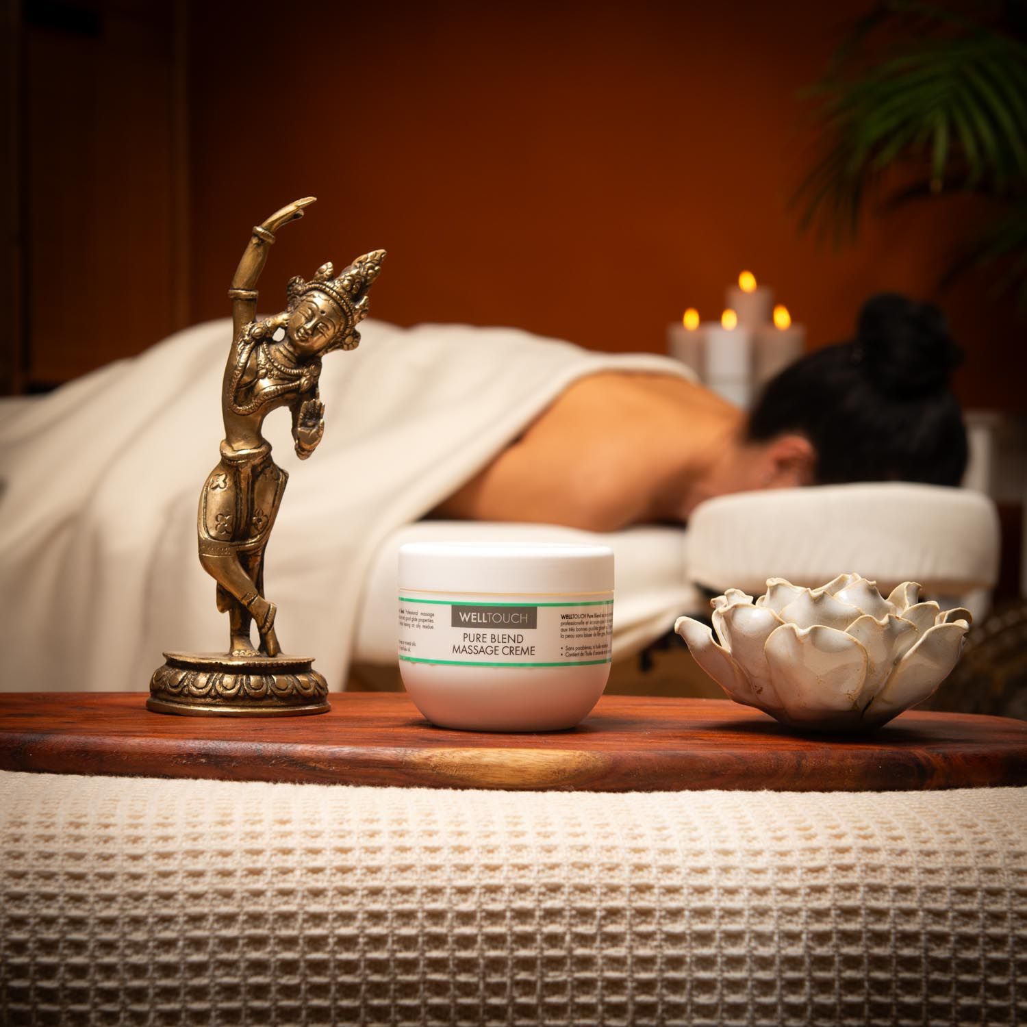 Witte crème pot met groene label. Opschrift: Welltouch Pure Blend Massage Creme. Voor massage scène.