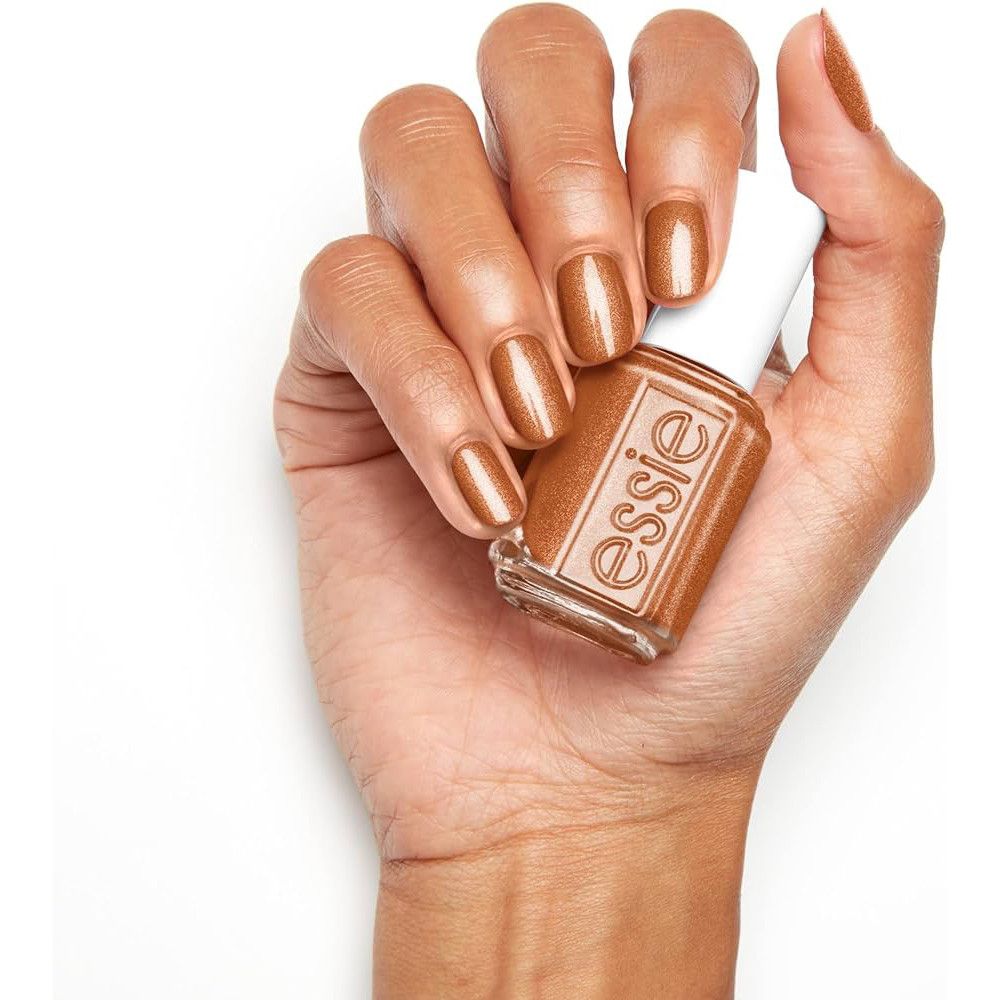 Hand met gelakte nagels en nagellakflesje. Flesje met witte dop, bruine lak, merk Essie.