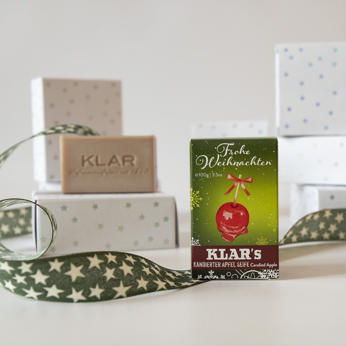 Zeepblok en verpakking met appelmotief. Cadeaudozen en lint op de achtergrond.