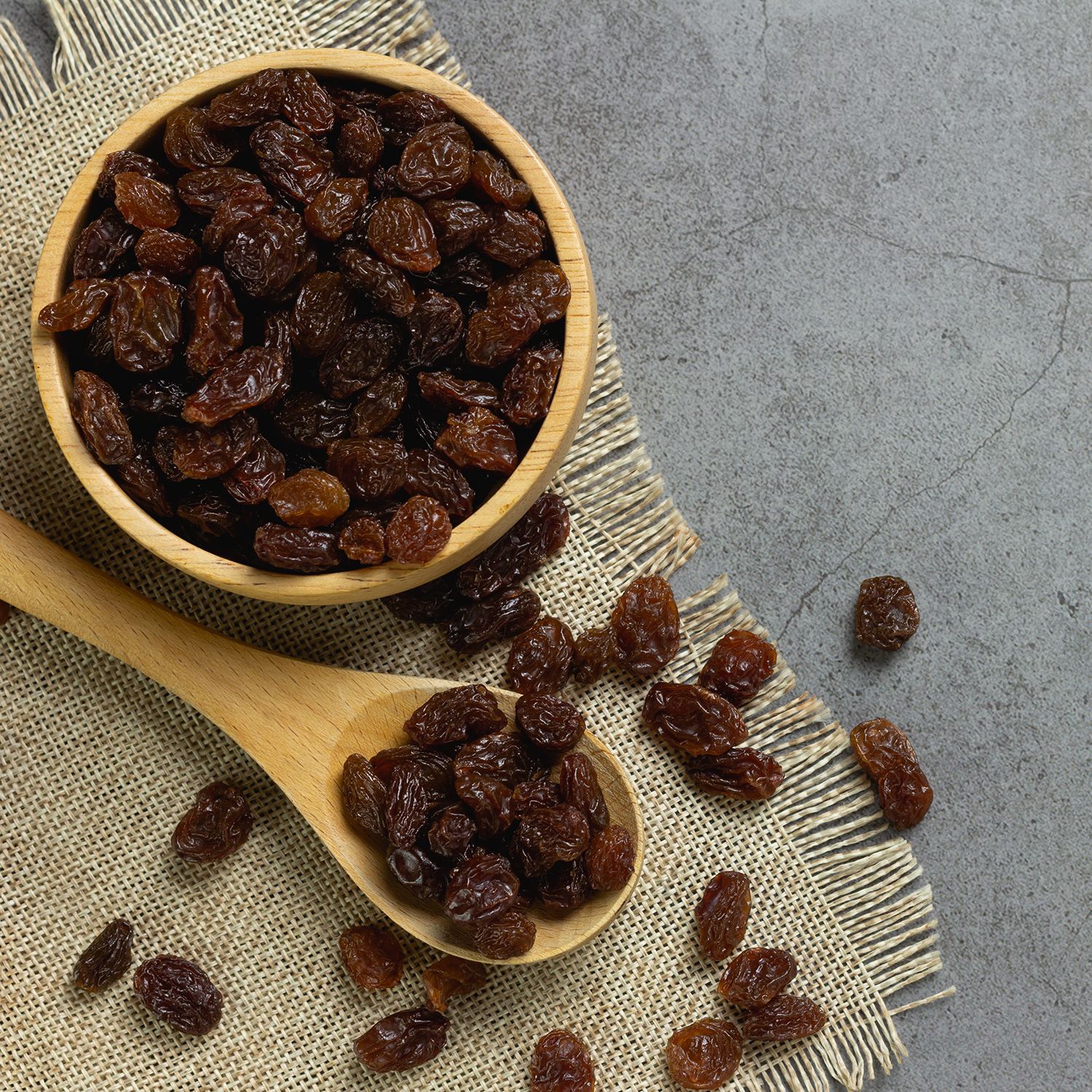 Raisins noirs dans un bol en bois sur du lin.
