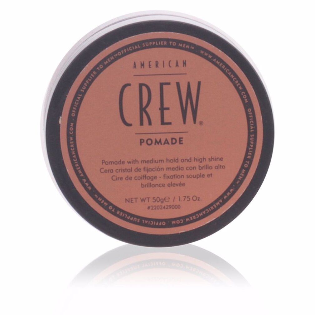 Ronde zwarte pot met bruin deksel. Opschrift: AMERICAN CREW. Pomade. Netto 50g/1.75 Oz. Reflectie.