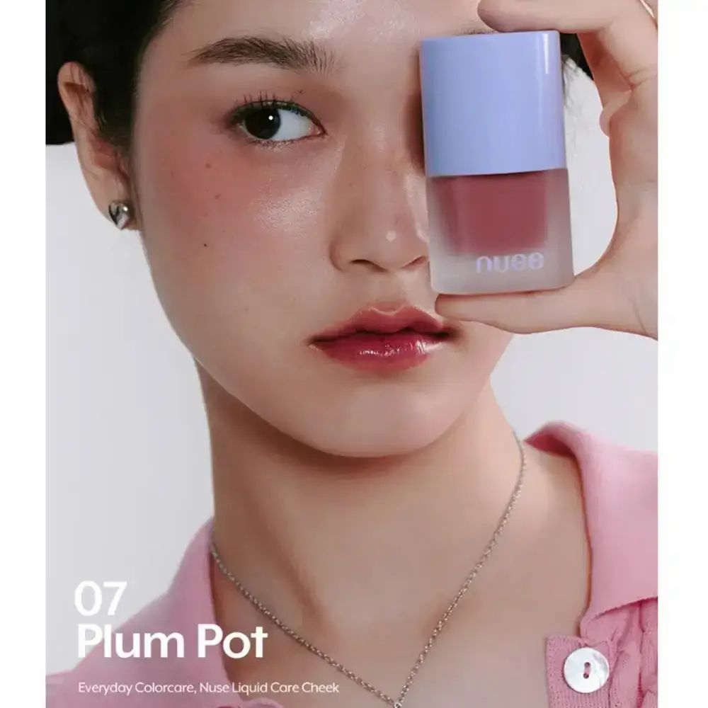 Een vrouw houdt een flesje vloeibare blush voor haar gezicht. Er is blush aangebracht op de wang. Op het product staat "07 Plum Pot".