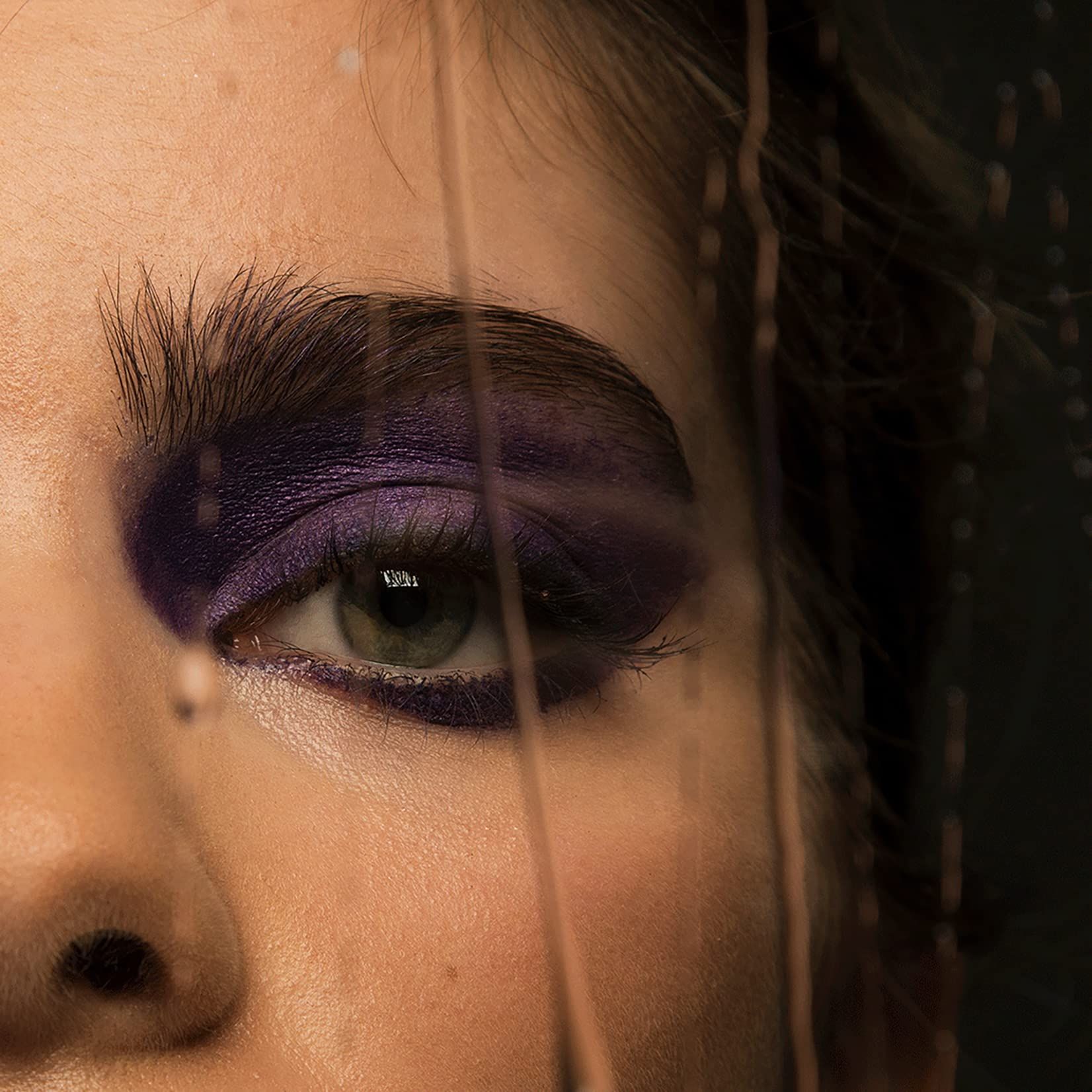 Oog met paarse oogschaduw. Wenkbrauw. Gedeeltelijk bedekt door een transparant oppervlak.