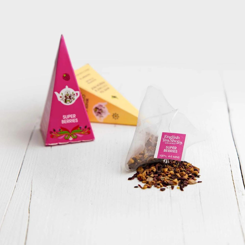 Roze en gele piramideboxen met theezakje en losse thee. Opschrift: Super Berries. Theezakje met opschrift Super Berries.