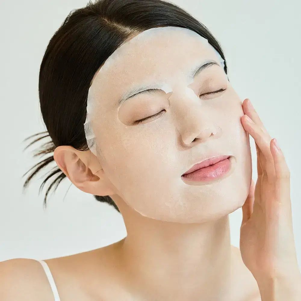 Vrouw met gezichtsmasker. Masker bedekt de huid. Hand raakt wang aan.