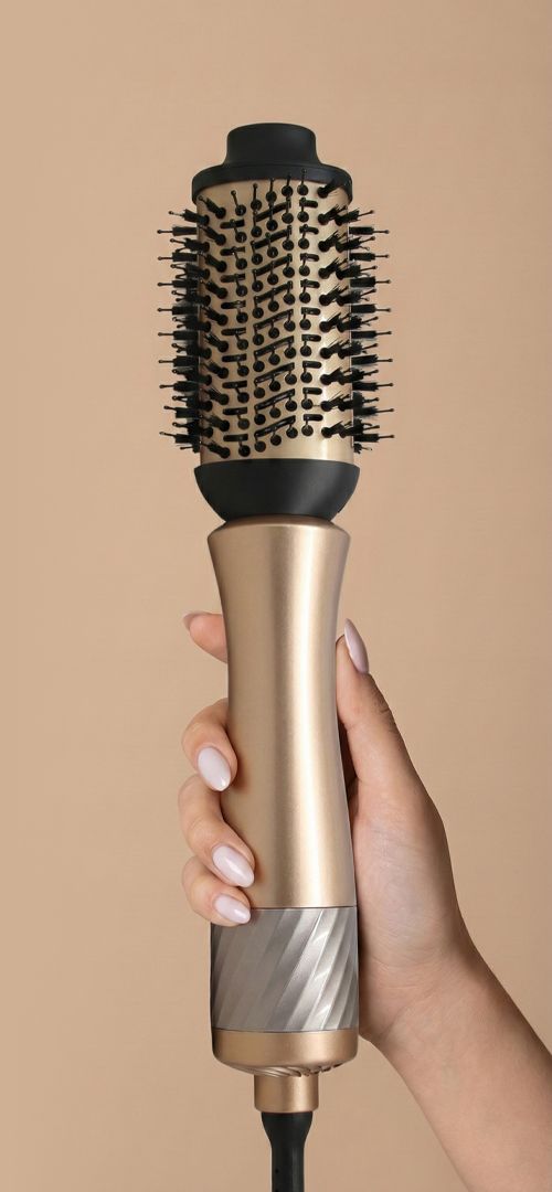 Gouden stylingborstel met zwarte ronde borstel en borstelharen, vastgehouden door een hand.