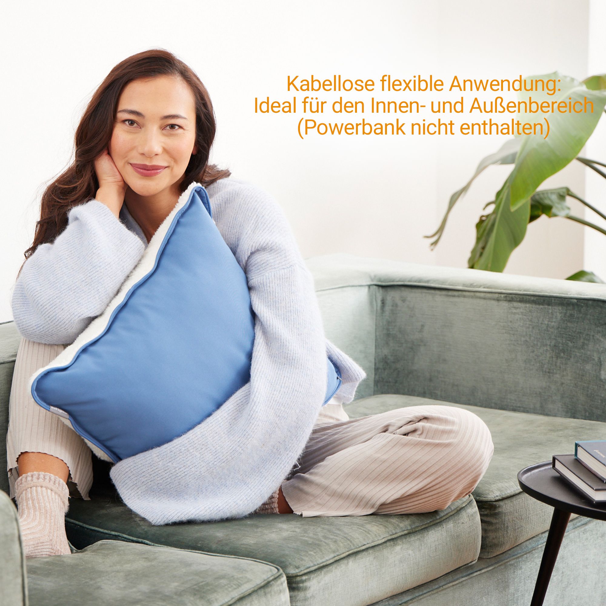Vrouw houdt een blauw verwarmingskussen vast dat op een bank ligt.
