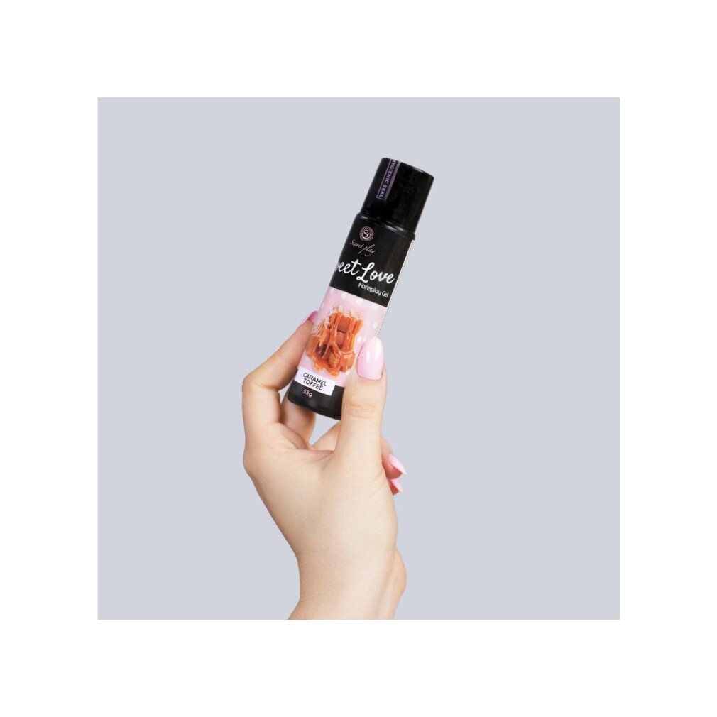 Hand die een fles Sweet Love Foreplay Gel Caramel Toffee, 55g, vasthoudt.