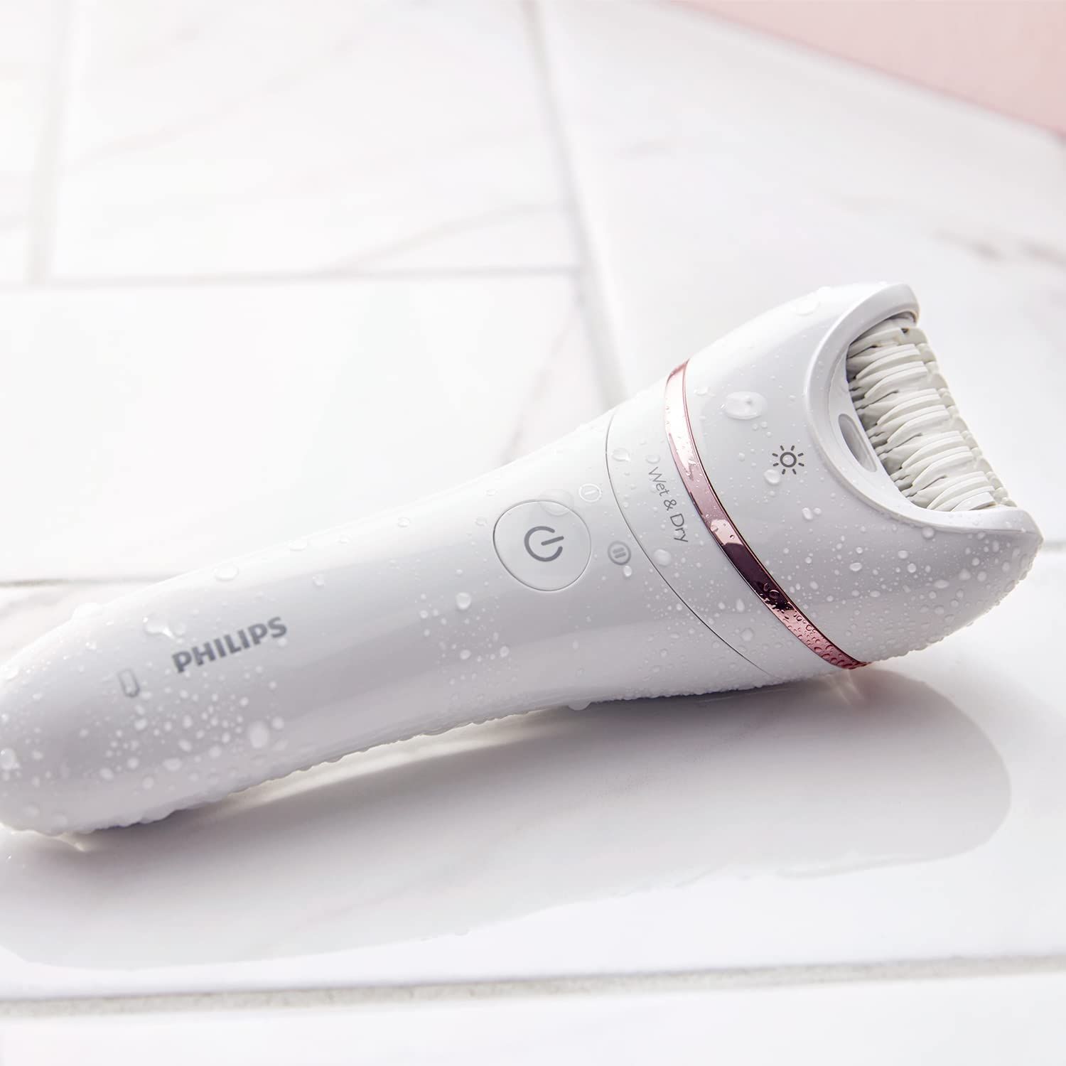 Épilateur blanc avec gouttes d'eau. Inscription Philips, Wet & Dry. Sur une surface carrelée.