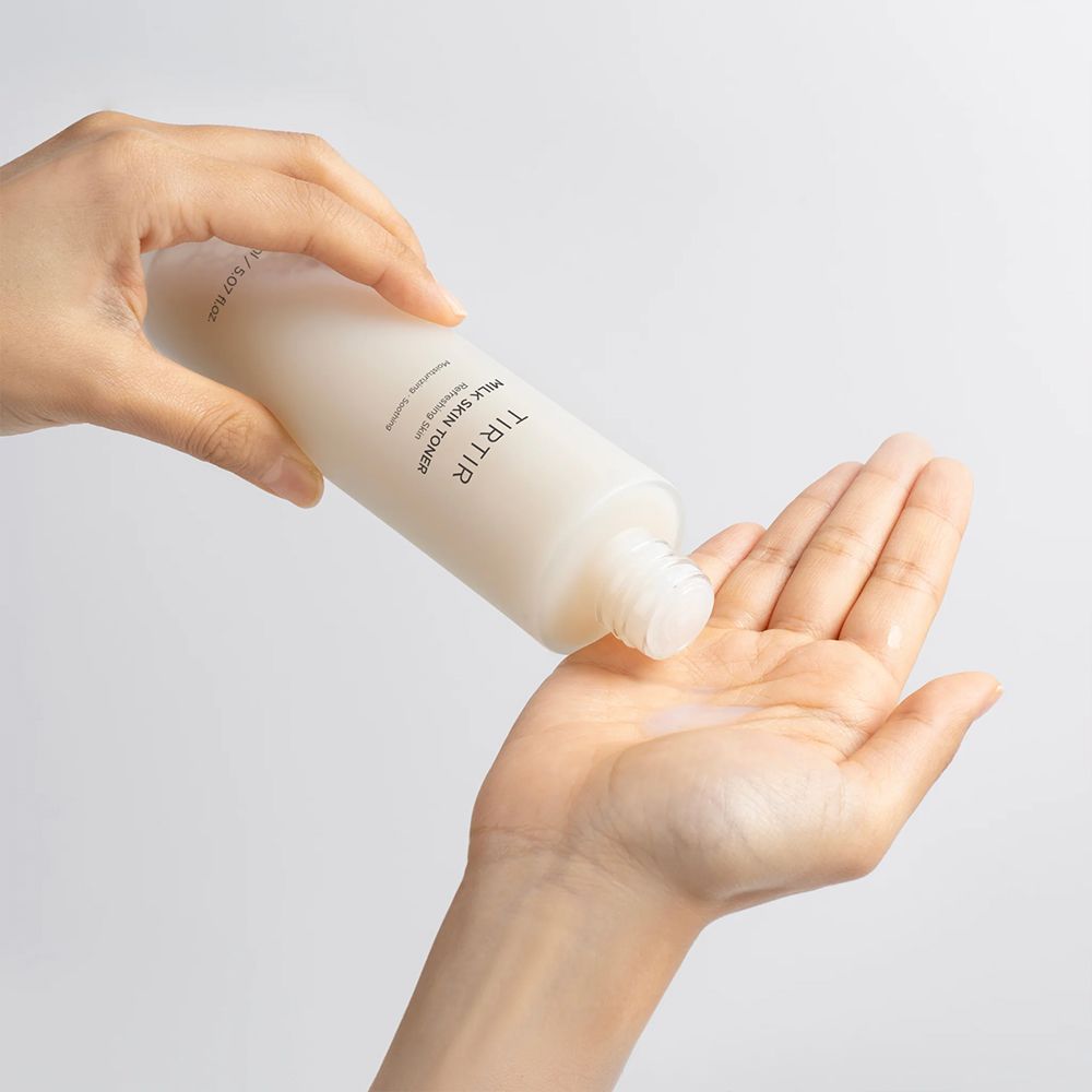 Mains versant le TIRTIR Milk Skin Toner d'une bouteille dans la paume.
