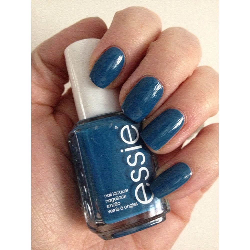 Blauwe nagellak van Essie. Fles in hand, nagels gelakt. Opschrift: nail lacquer, nagellack, vernis à ongles.