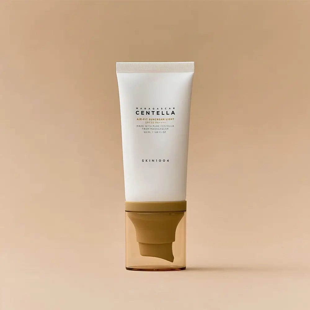 Tube blanc avec bouchon marron. Inscription: MADAGASCAR CENTELLA AIR-FIT SUNCREAM LIGHT. Nom du produit et marque visibles.